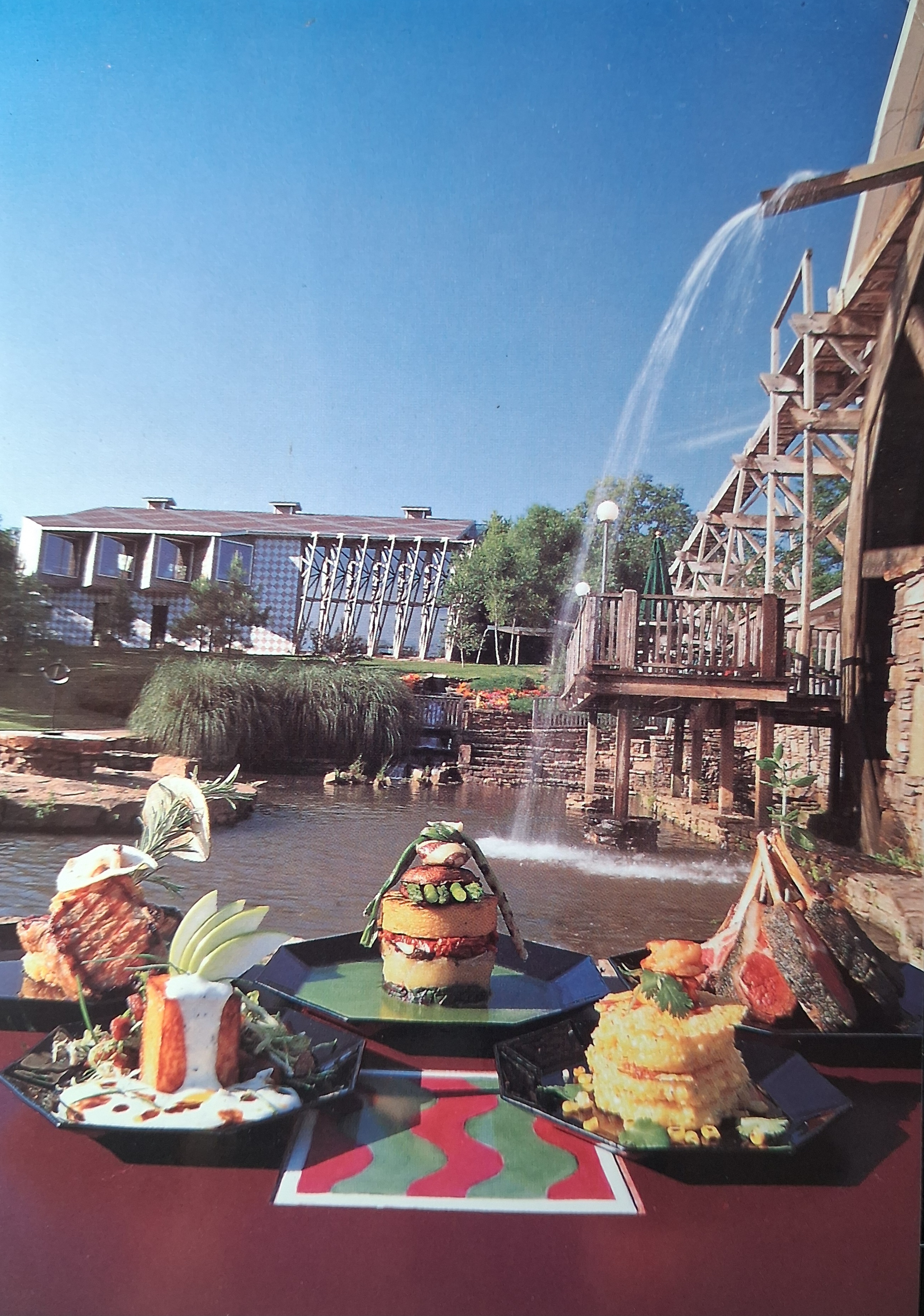 Postcard photograph of five plated dishes beside the historic mill and restaurant.